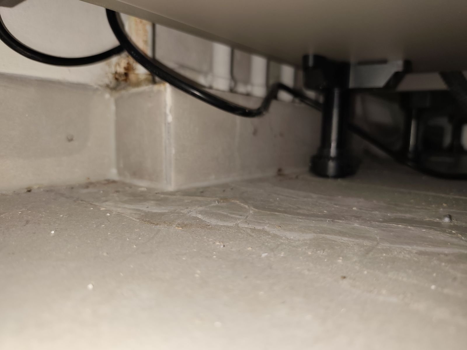 Inspection sous un meuble de cuisine révélant des traces d'humidité – VRL EAU